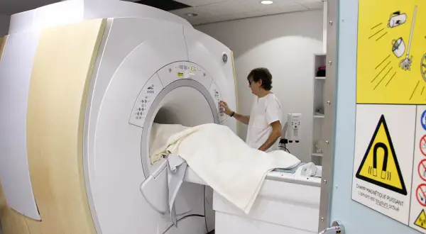 Un technicien prépare un patient pour une IRM. La question "combien d'IRM peut-on faire par an" dépend de la prescription médicale.