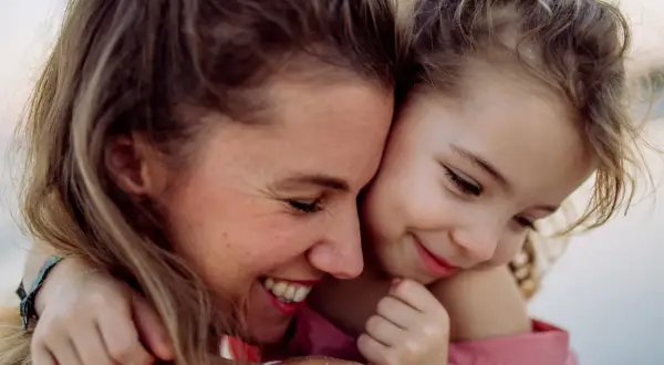 Een moeder en dochter knuffelen. De dochter vraagt zich af: "hoe oud ben je in groep 3?
