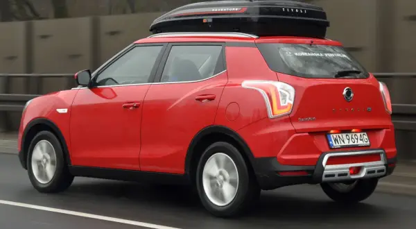 Czerwony SsangYong Tivoli z boxem dachowym, gotowy na podróż. Wiele pozytywnych ssangyong tivoli opinie potwierdza jego wszechstronność.