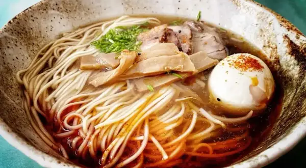 A miseczce shoyu ramen z makaronem, plastrami mięsa, bambusem i jajkiem na twardo, posypane przyprawami.