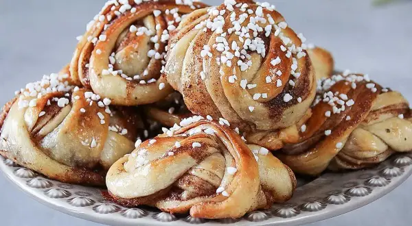En hög med nybakade kanelbullar, perfekta för ett kanelbullar recept. Strösslade med pärlsocker.