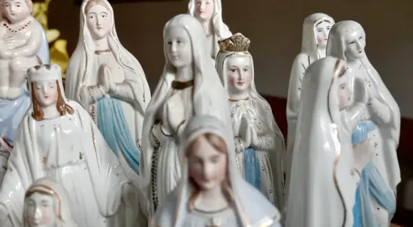 Eine Sammlung von Marienfiguren, die an das maria geburt datum erinnern. Die Figuren tragen weiße Gewänder und einige haben Kronen.