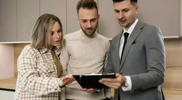 Para młodych ogląda ofertę mieszkania z agentem nieruchomości. Wynajmujący omawia szczegóły umowy.