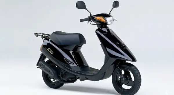 Ciclomotor negro Yamaha Jog, un clásico de los ciclomotores de los 90, con asiento y parrilla trasera.