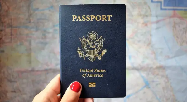 Dłoń trzyma paszport USA na tle mapy. Zastanawiasz się, ile trwa wyrobienie paszportu w trybie przyspieszonym?