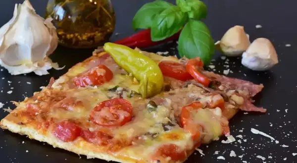 Pyszny kawałek pizzy z pomidorami i papryką, czosnkiem i bazylią. Zastanawiasz się, ile może leżeć pizza w lodówce?