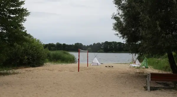 Plaża nad jeziorem Lednica z siatką do siatkówki i namiotami tipi.