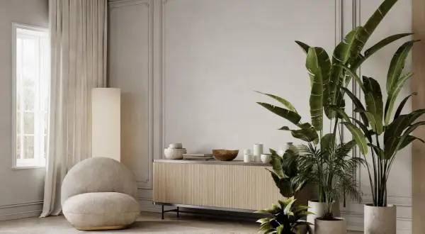 Elegancka sztukateria w salonie inspiracje: przytulny fotel, drewniana komoda i bujna zieleń tworzą harmonijną przestrzeń.