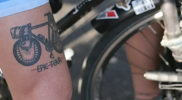 Tatuaż rowerowy z napisem "EPIC TOUR" na ramieniu rowerzysty.