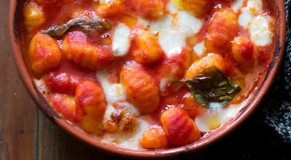 Gnocchi alla napoletana fumanti in terracotta, con pomodoro filante e basilico fresco. Un abbraccio di sapori autentici.