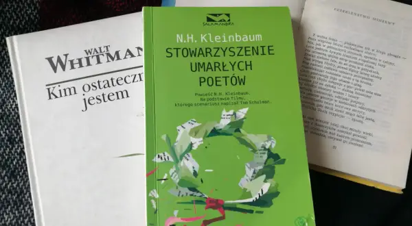 Zielona okładka książki "Stowarzyszenie Umarłych Poetów" N.H. Kleinbauma. Obok biała książka Walta Whitmana.