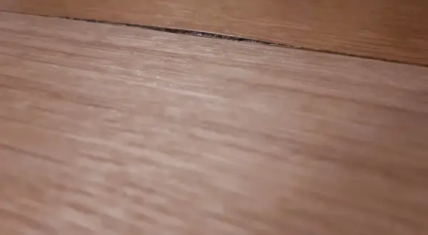 Szczelina na blacie kuchennym wymaga naprawy. Widoczne drewniane słoje sugerują potrzebę renowacji.