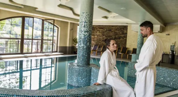 Para relaksu w Hotel Elbrus Spa & Wellness. Para w szlafrokach przy basenie, z widokiem na góry.