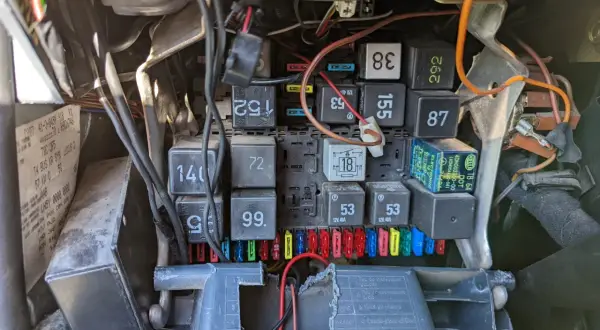 Widok na skrzynkę bezpieczników i przekaźników w samochodzie. Widać bezpiecznik od kierunkowskazu, oznaczenie 18, oraz inne elementy instalacji elektrycznej.