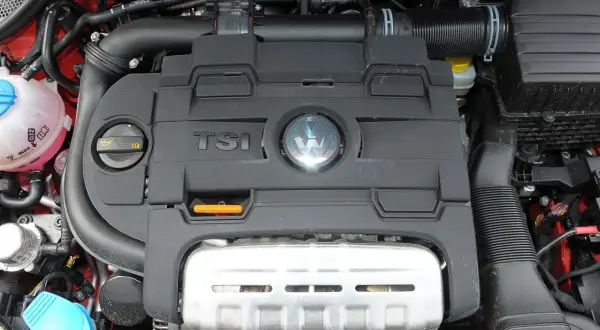 Silnik TSI w Volkswagen Polo 6R. Widoczny czarny plastikowy dekiel z logo VW i napisem TSI, a pod nim metalowa osłona.