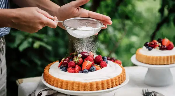 Ein sommerlicher Kuchen mit frischen Beeren wird mit Puderzucker bestäubt.
