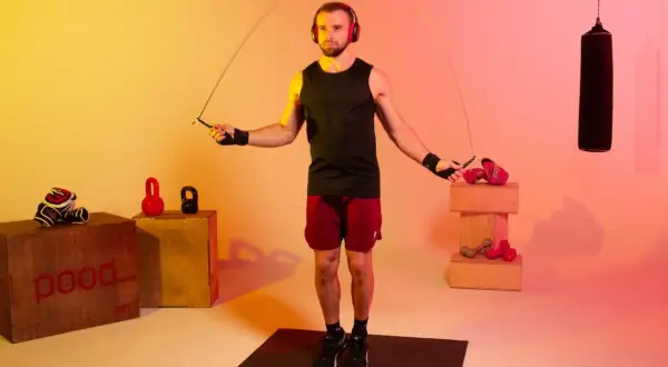 A boxer with headphones jumps rope, a common training method to improve stamina and agility. How long do boxers jump rope? It varies, but often for 10-15 minutes per round.