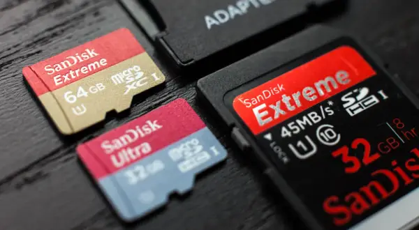 Karty pamięci SanDisk Extreme i Ultra, w tym 64GB microSDXC i 32GB microSDHC, obok adaptera. Różnice między SDXC a SDHC są widoczne.