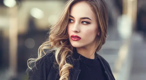 Blondynka z burzą falowanych włosów i wyrazistymi, czerwonymi ustami. Idealny kolor pomadki dla blondynek, który podkreśla urodę.