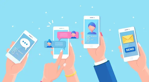 Ręce trzymają telefony, na których widać ikony i dymki czatu, symbolizujące komunikatory internetowe.