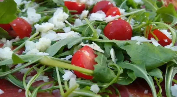 Pizza z rukolą, pomidorkami i parmezanem. Rukola właściwości zdrowotne dodają jej lekkości i świeżości.