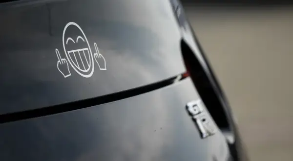 Lachendes Smiley-Gesicht mit Mittelfingern als Aufkleber am Auto. Welche Aufkleber am Auto sind erlaubt?
