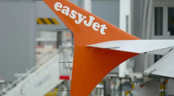 Pomarańczowy ogon samolotu easyJet z białym logo, gotowy do lotu. Idealny na bagaż podręczny.