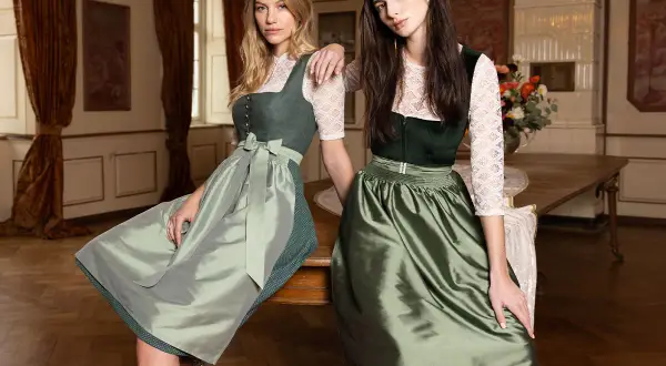 Zwei Frauen in Tracht. Die eine trägt ein grünes Dirndl mit einer hellgrünen Schürze, die andere ein dunkelgrünes Dirndl mit einer glänzenden, grünen Schürze. Eine dirndlschürze braun wäre eine schöne Ergänzung.