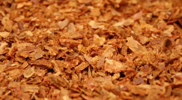 Zbliżenie na drobno pokruszony, brązowy propolis.