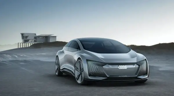 Srebrny Audi A9 AI:CON na tle nowoczesnego domu na wydmach. Futurystyczny design, podświetlany grill.