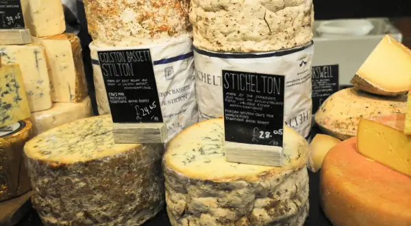 Gros plans sur des fromages anglais, dont le Stilton Colston Bassett et le Stichelton, avec leurs étiquettes de prix.