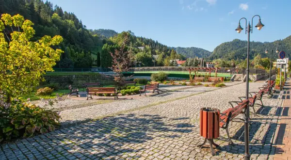 Urokliwa promenada nad Grajcarkiem, z ławkami i latarniami, zaprasza do spacerów wśród zieleni i górskiego krajobrazu.