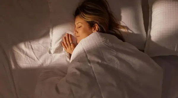 A woman sleeps peacefully, her hands clasped. The image captures the quiet stillness of sleep, hinting at the subtle rhythm of her respiratory rate while sleeping.