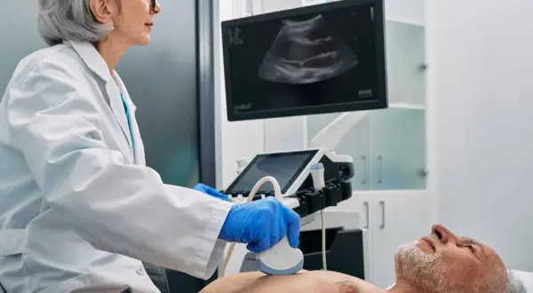 Ärztin führt Ultraschalluntersuchung durch. Der Bildschirm zeigt ein Bild, das auf eine Untersuchung von Organen oder Lymphknoten hindeutet.