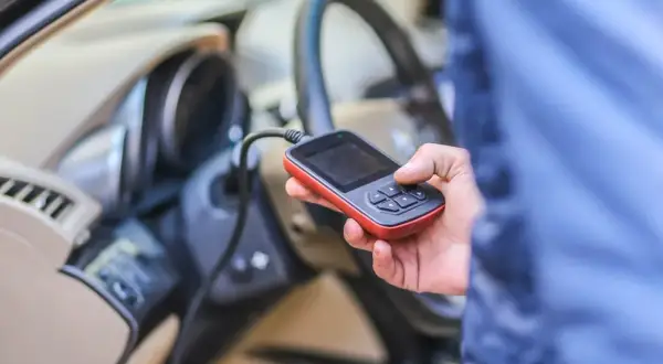 Diagnostyka Renault: ręka trzyma czytnik OBD, który może wykryć błąd DTC B1267.