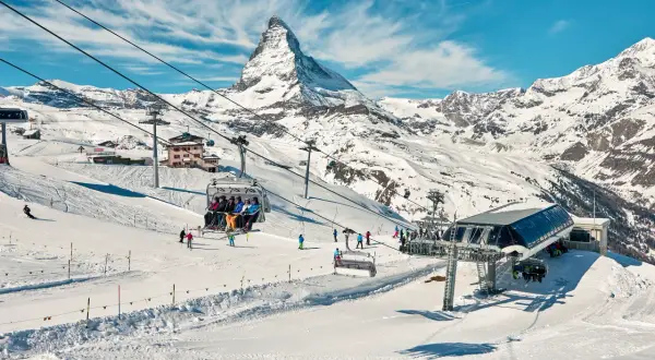 Widok na góry i stoki narciarskie z kolejką linową. Widać znaki na stokach narciarskich, narciarzy i snowboardzistów.