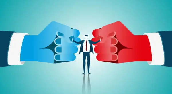 Biznesmen między dwoma gigantycznymi pięściami (niebieską i czerwoną) symbolizuje, jak działa arbitraż.