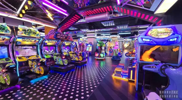 Kolorowy park rozrywki w Łodzi z maszynami do gier, w tym motocyklami i wyścigami.