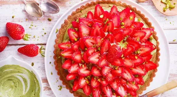 Tarte fraise pistache, une gourmandise aux couleurs vives, garnie de fraises fraîches et de pistaches concassées sur une crème onctueuse.