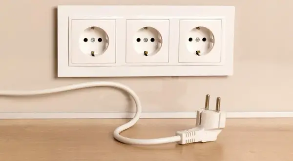 Biały kabel biegnie od gniazdka do wtyczki. Dowiedz się, jak zamaskować kable na ścianie, by uniknąć bałaganu.