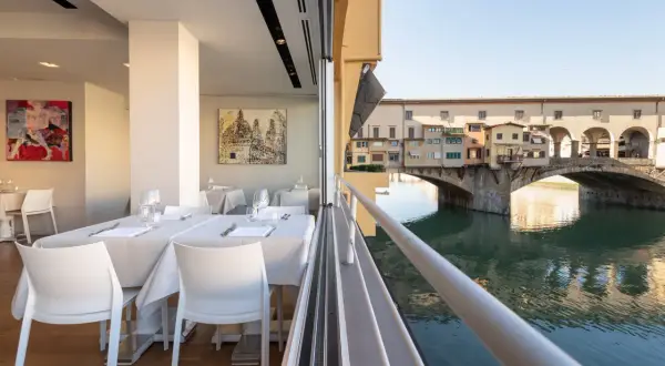Tavoli apparecchiati con vista sul Ponte Vecchio: un'idea su dove mangiare a Firenze.