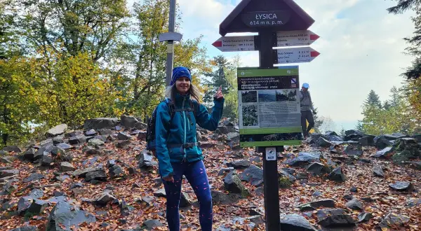 Kobieta na szczycie Łysica, 614 m n.p.m., przy drogowskazie. Jesienny szlak, liście i kamienie.