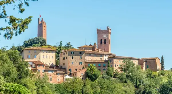Borgo medievale di San Miniato con torri imponenti e case in pietra, immerso nel verde della campagna toscana.