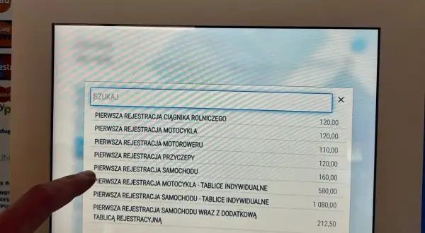 Na ekranie terminala widać listę usług związanych z rejestracją pojazdów. Sprawdzam, ile kosztuje przerejestrowanie samochodu.
