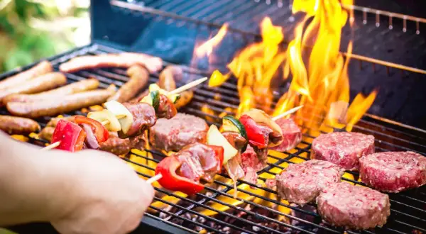 Brochettes de viande et légumes, saucisses et steaks sur un barbecue au barbecue, avec des flammes vives.