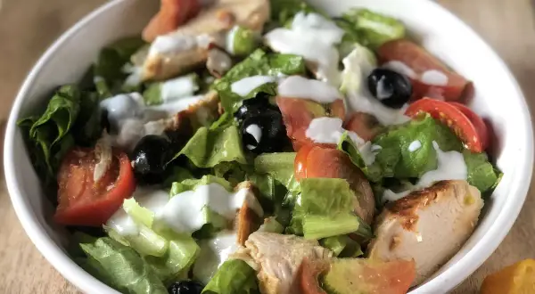 Insalata di pollo sfiziosa con lattuga croccante, pomodoro, olive nere e un dressing cremoso. Perfetta per un pasto leggero e gustoso.