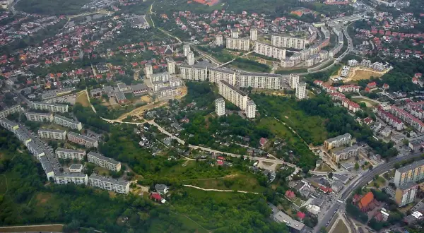 Widok z lotu ptaka na osiedle mieszkaniowe w Gdańsku Suchanino. Długie bloki mieszkalne otoczone zielenią i drzewami.
