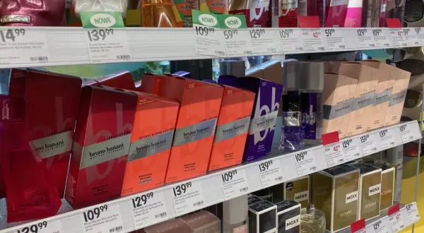 Półki z perfumami w drogerii, w tym flakony w kształcie czaszek i pudełka z marką Bruno Banani.