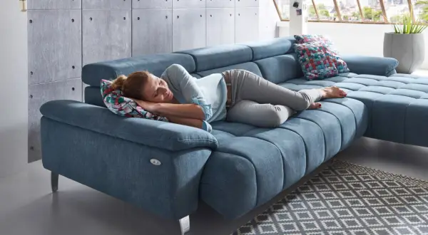 Kobieta śpi na niebieskiej sofie, która jest tak wygodna, że można zapomnieć, czym się różni sofa od kanapy.