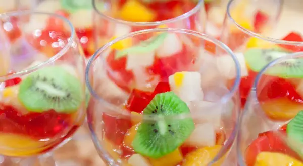 Kolorowe galaretki z owocami, w tym kiwi, w kieliszkach. Czy wiesz, dlaczego galaretka z ananasem nie tężeje?